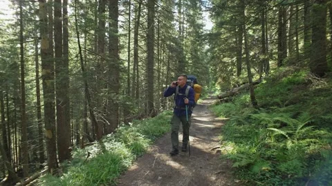 A man with a backpack, on a hike and talks on the phone Stock Footage 236984096