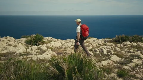 Man with backpack hike on ridge of mountain cliff Stock Footage 261869663
