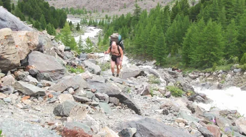 Man with backpack hiking across mountain Видео 22514201