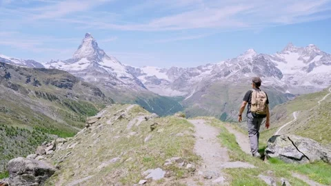 Man with backpack hiking in the alps, looking at the famous matterhorn mountain 스톡 동영상 339097225