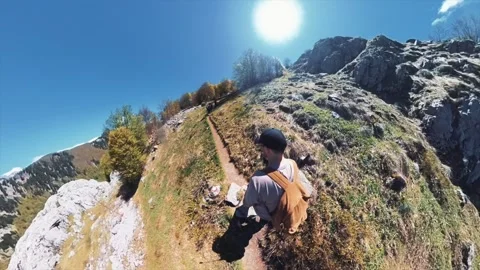 A man with a backpack is hiking up a mountain surrounded by nature Stock Footage 277196814