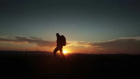 Man with backpack hiking in the sunset. Stops and looks at the sunset Stock Footage 135119589