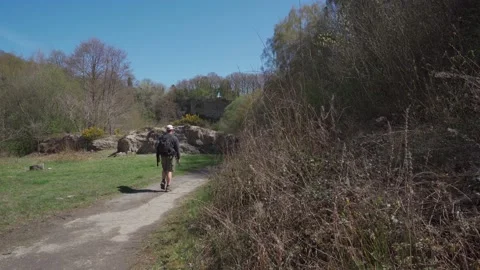A man with a backpack hiking through a quarry Video stock 155618146