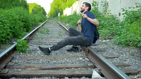 A man with a backpack on his back sat down to rest on the rails. Travel on Video stock 154576378