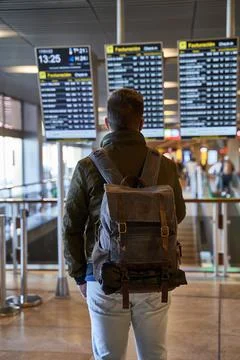 Man with backpack looking train schedules in train station. Train or airport  Stock Photos