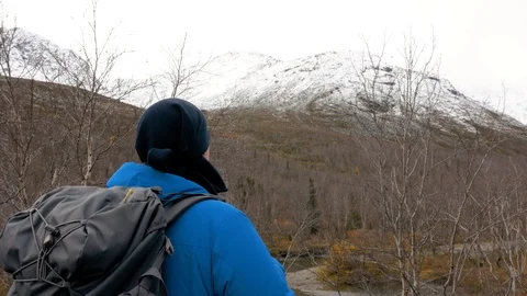 A man with a backpack looks at the mountains. Before him is a beautiful Video stock 97298364