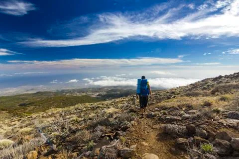 Man with backpack on path in semidesert with stones and blue sky Foto stock