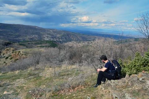 A man with a backpack resting and contemplating scenic panorama Stock Photos