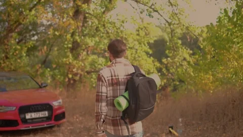 Man with backpack returns from hiking in the forest, tired, sitting in car in wo Stock Footage 278277301