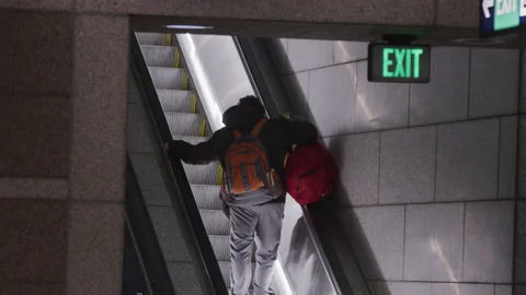 Man with backpack riding escalator out of Seattle subway station Stock Footage 235472034