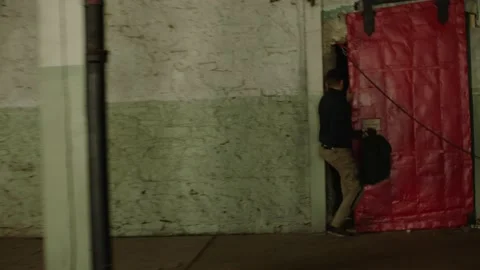 Man with backpack runs away from another man chasing him in a warehouse and thro Stock Footage 199455270