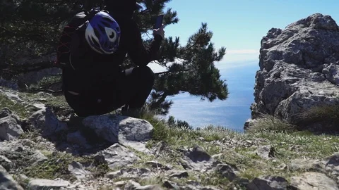 Man with backpack sits on rock photos mountains by blue sea Video stock 103282983