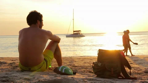 Man with Backpack Sitting on the Beach Stock Footage 62420736