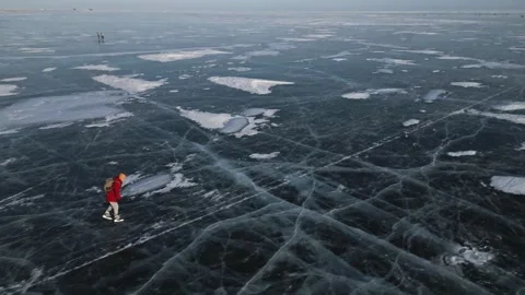 Man with a backpack is skating on the blue transparent ice of the lake Baikal Stock Footage 278020181