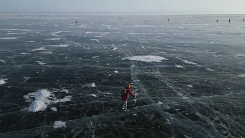 Man with a backpack is skating on the blue transparent ice of the lake Baikal Stock Footage 278020612