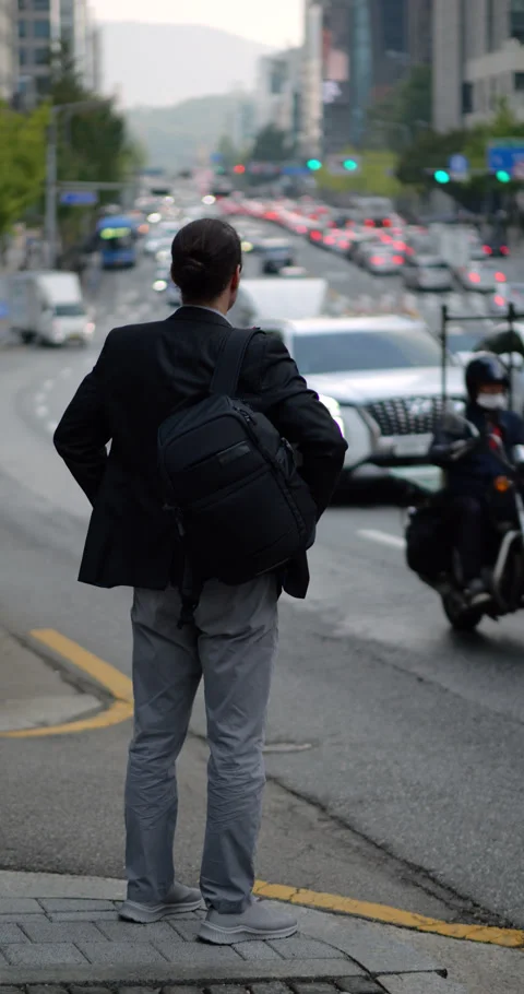 Man with backpack stand at roadside looking to oncoming traffic Stock Footage 303989802