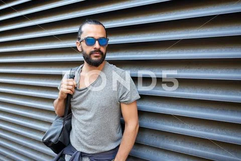 Man with backpack standing at city street wall Stock Photos