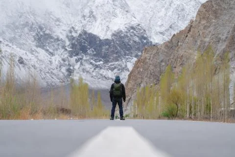 A man with backpack standing on empty road in northern Pakistan Stock Photos