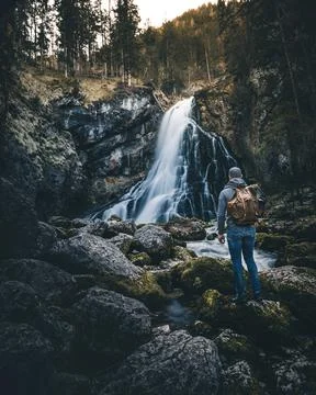 Man with backpack standing in front of waterfall Stock Photos