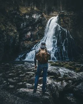 Man with backpack standing in front of waterfall Stock Photos