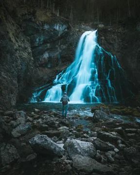 Man with backpack standing in front of waterfall Stock Photos