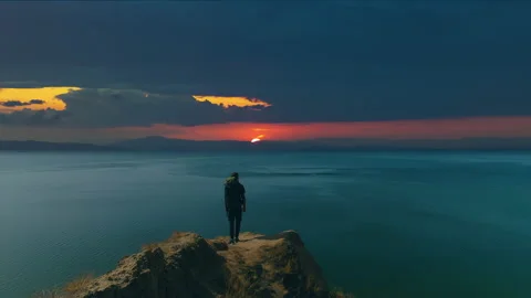 The man with backpack standing on the mountain edge on the seascape background Stock Footage 143033290