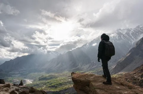 A man with backpack standing on mountain peak Stock Photos