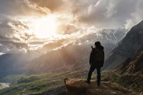 A man with backpack standing on mountain peak and bright sunlight Stock Photos