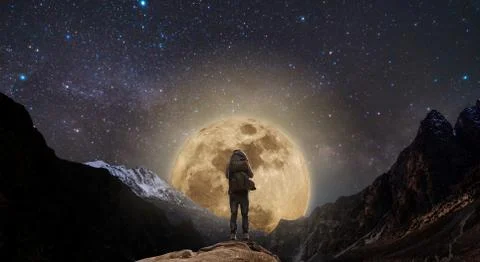 A man with backpack standing on mountain peak at night, and full moon on the sky Stock Photos