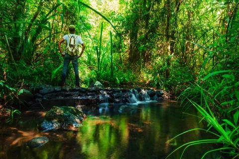 A man with a backpack standing on a rock in the stream Foto stock