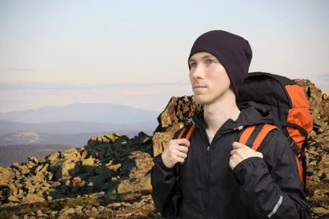 Man with backpack standing on top of a mountain and looks into the distance Stock Photos