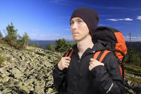 Man with backpack standing on top of a mountain and looks into the distance Stock Photos
