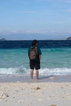 Man with Backpack Standing on Tropical Beach 스톡 사진