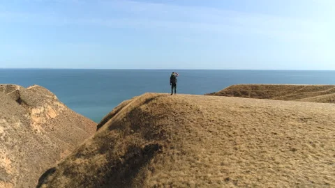 The man with backpack stands on the mountain top against the sea Stock Footage 143041490