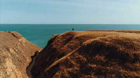 The man with backpack stands on the mountain top against the sea Stock Footage 151366888