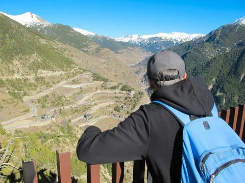 A man with a backpack stands on top of a mountain and admires the landscape Foto stock