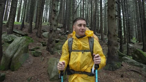 A man with a backpack through the forest in the rain. The tourist looks around Stock Footage 218438913