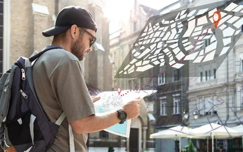 Man with backpack traveling around city holding map in hands, searching route, d Stock Photos