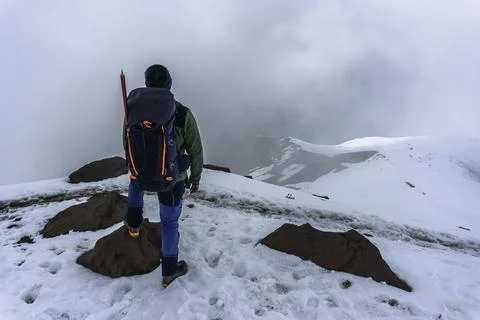 Man with backpack trekking in mountains. Cold weather Stock Photos