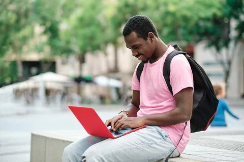Man with backpack using a laptop outdoors. Stock Photos