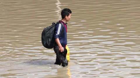 A man with a backpack wades through a flooded street Stock Footage 342520382