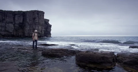 A man with a backpack walkig along the coast. Russky Island, Pacific, Steadycam Stock Footage 100764247