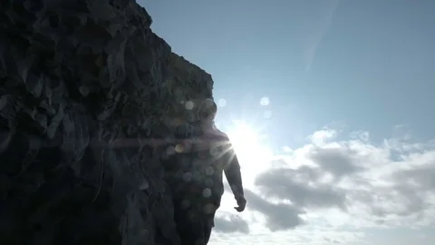 Man with a backpack, walking along the shore of Black Sand Beach in Iceland Stock Footage