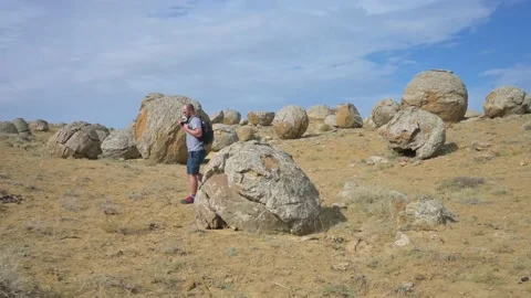 Man with backpack walking around the valley with sphere stones in Kazakhstan Stock Footage 218999792
