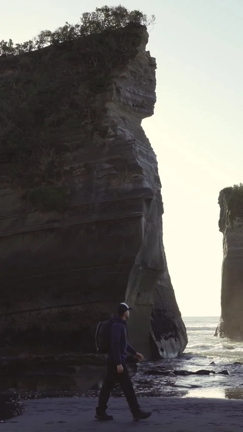 Man with backpack walking by the beach with amazing rock formations known a.. Stock Footage 289100357