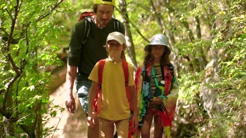 Man with backpack walking with boy and girl at road in mountains. Travel Stock Footage 140905946