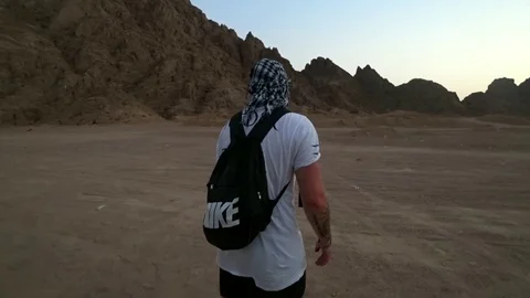 A man with a backpack is walking in the desert Video stock 98007515