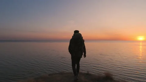 The man with backpack is walking on the mountain near the sea. slow motion Stock Footage 143562539