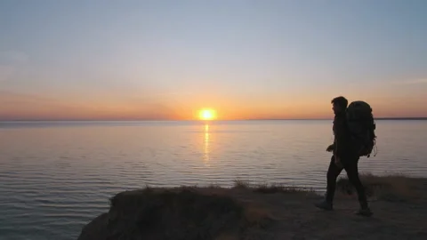 The man with backpack is walking on the mountain near the sea. slow motion Video stock 143562762
