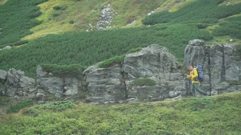 A man with a backpack walking in the mountains against the background of rocks Stock Footage 229001858